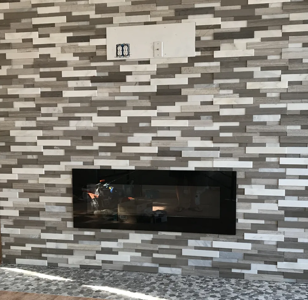 Custom stone fireplace feature wall with pebble tile hearth by Creative Construction Concepts