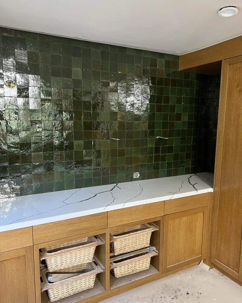 Green zellige tile surround with a custom wood vanity, by Creative Construction Concepts in Los Angeles