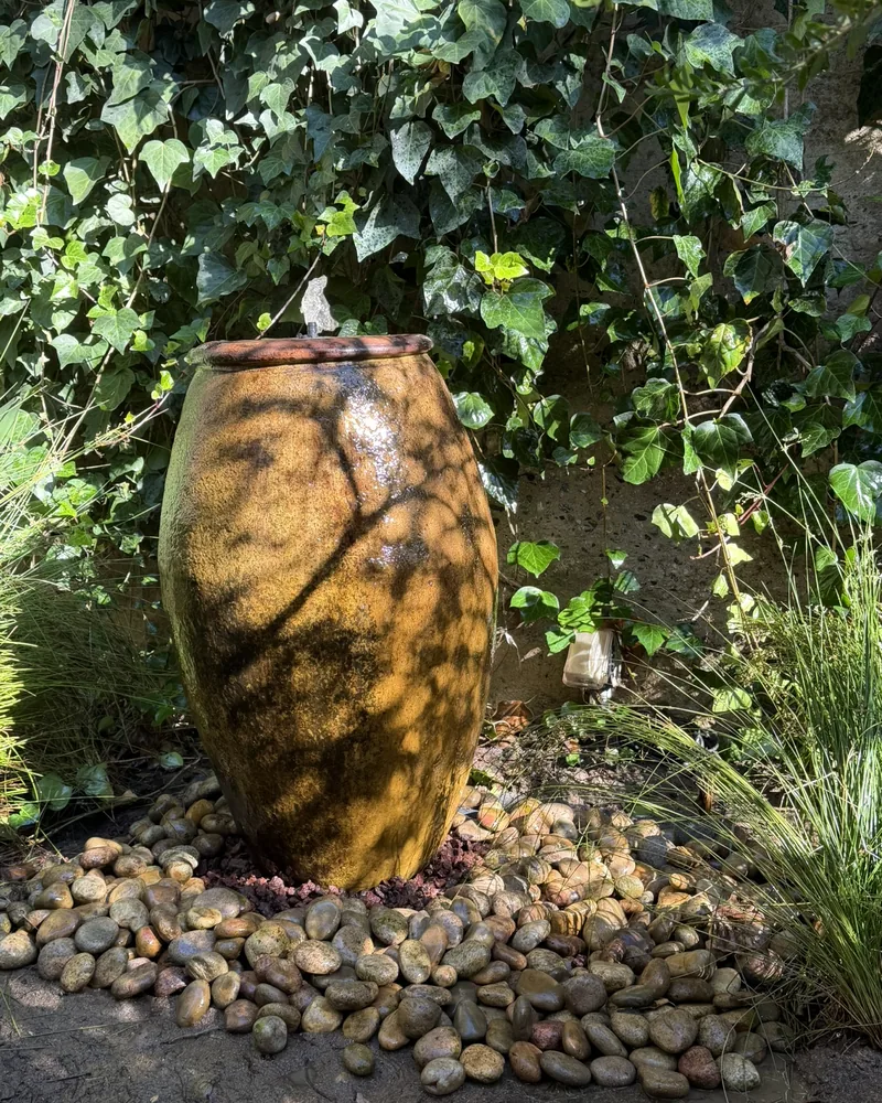 Ceramic urn fountain set in river rock, by Creative Construction Concepts in Los Angeles