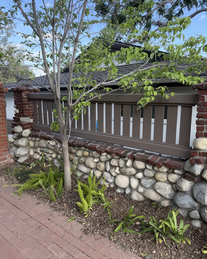 River-rock retaining wall with a brick walkway, by Creative Construction Concepts in Los Angeles