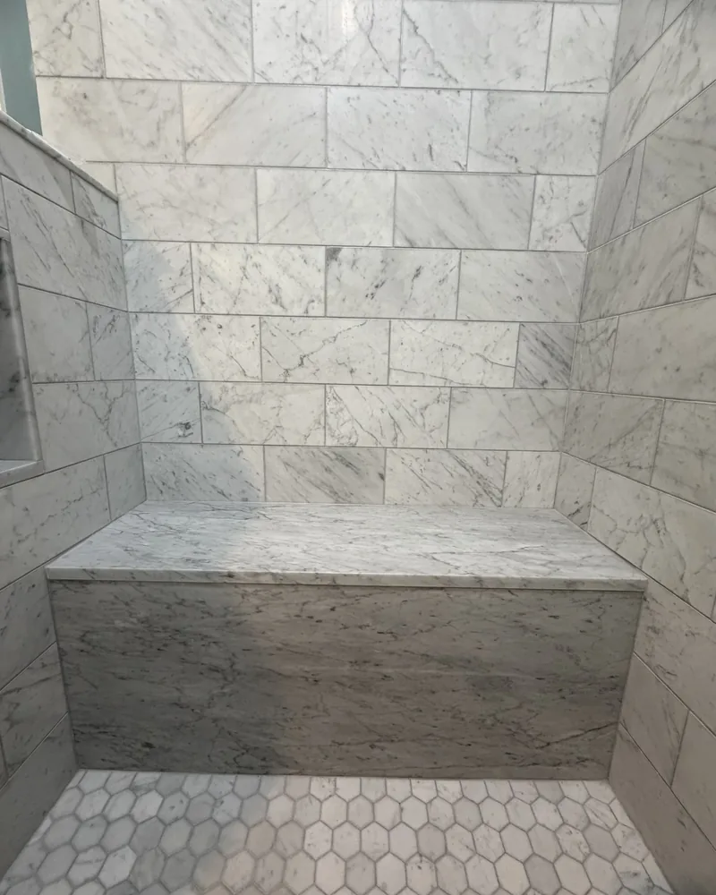 Marble shower with a full bench and hex mosaic floor, by Creative Construction Concepts in Los Angeles